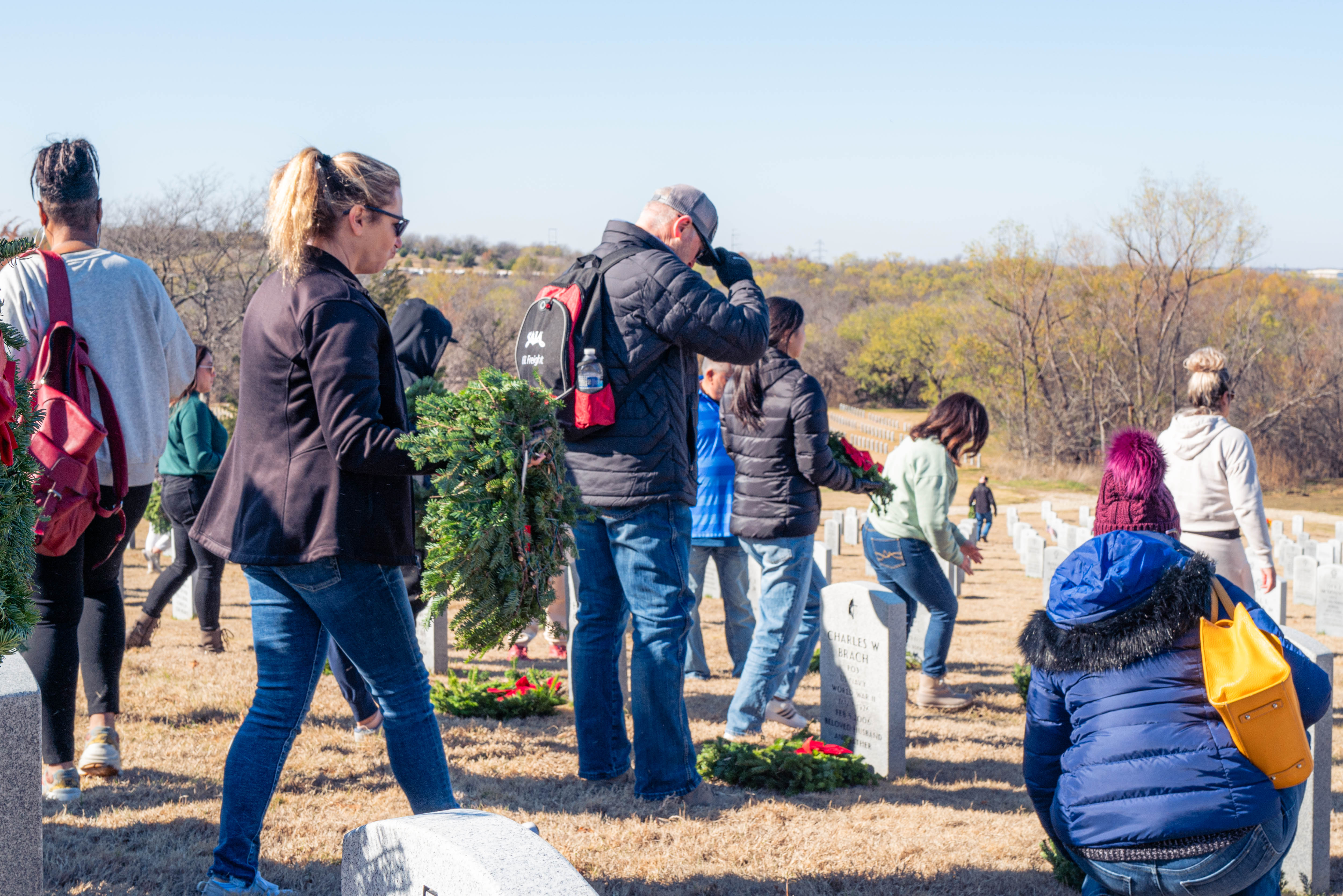 A local community member of the Dallas-Forth Worth area pays respects to a fallen veteran during the 2023 National Wreaths Acros America Day.